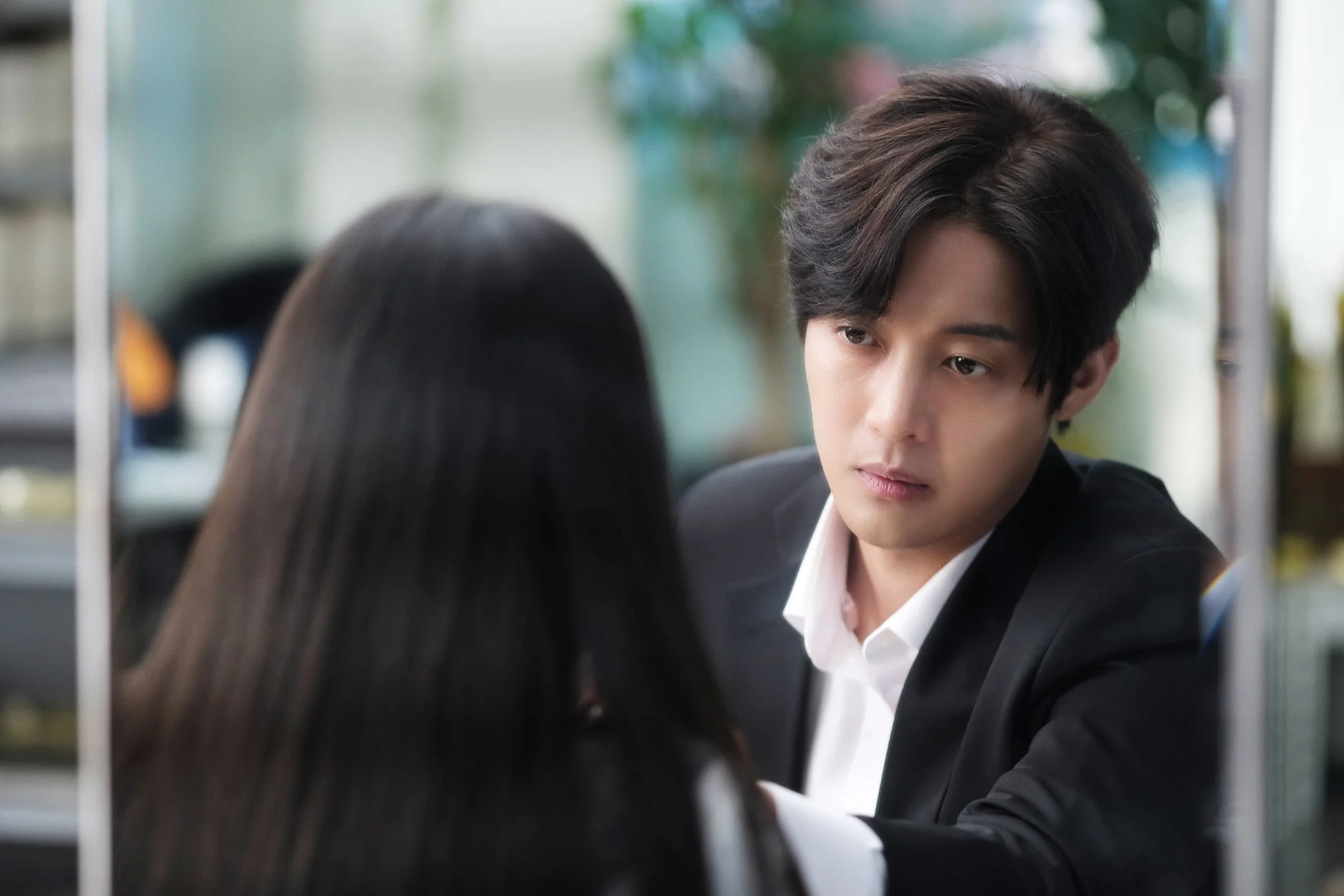 スーツを着た男性が、背中を向けている女性のほうを真剣な表情で見つめています。