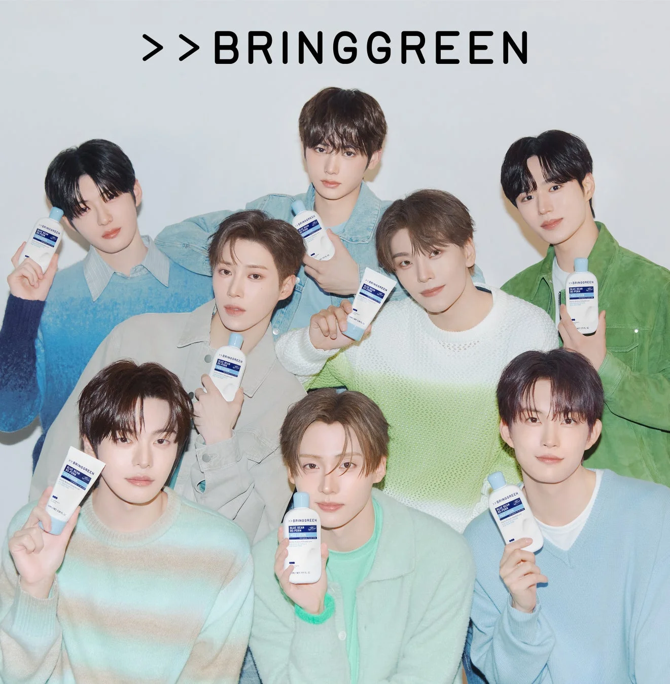 K-POPアイドルグループの男性8人が、BRINGGREENの「BLUE BEAN HYDRATING」スキンケア製品を宣伝する広告写真。パステルカラーの衣装で、爽やかで清潔感のある雰囲気を演出している。