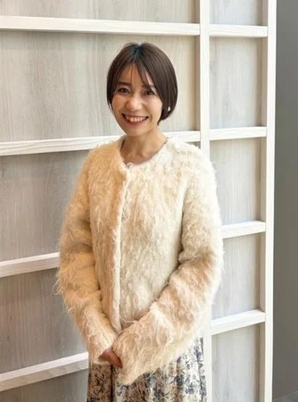 ショートヘアの女性が笑顔で立っています