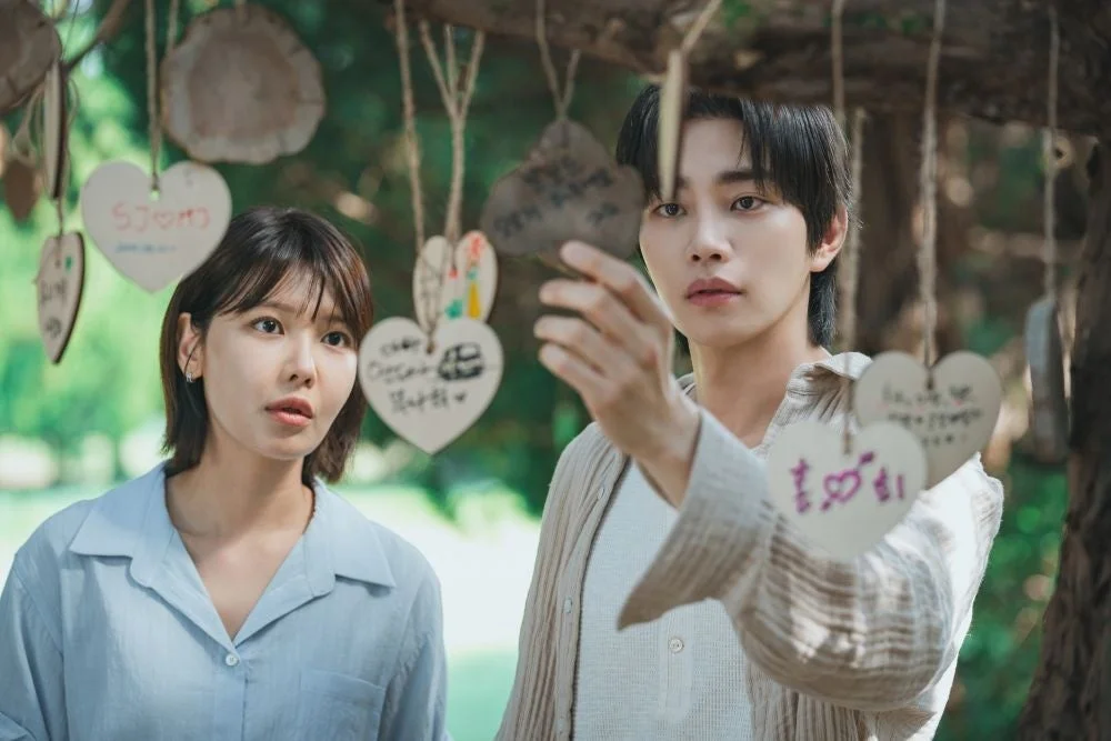 屋外でハート型の願い事を書いた木札が吊るされた木を見上げる男女