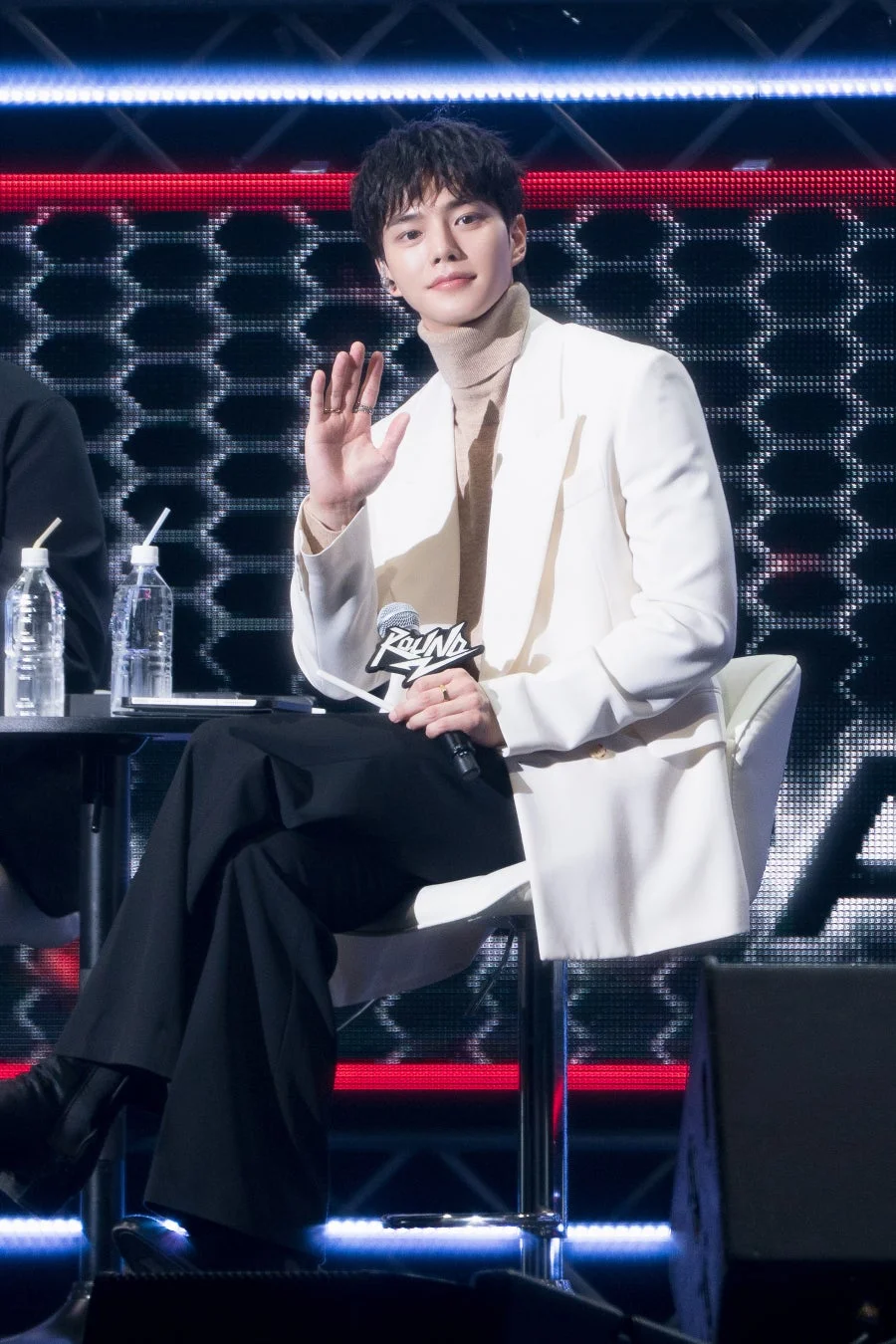 ステージ上でマイクを持ち手を振るソン・ガン