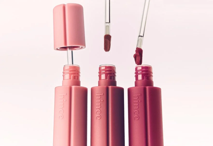 hinceブランドの液体リップ製品が3つ並べられています。それぞれ異なるピンク・レッド系の色合いで、アプリケーターが蓋から出ており、一つの蓋は開いている状態です。