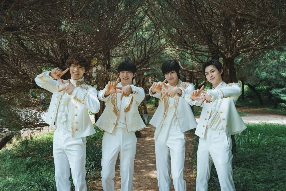 白いフリルと金色の装飾の衣装をまとった4人の若い男性