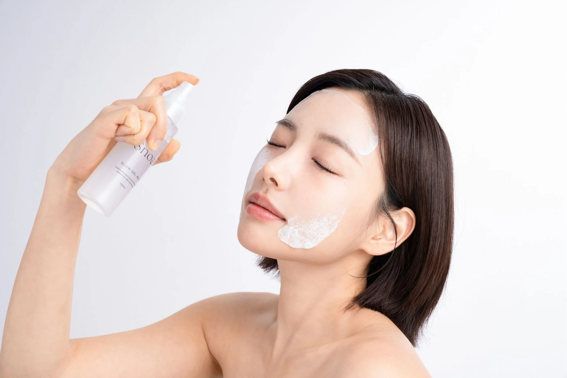 GLOWジェルミストを顔にスプレーする女性