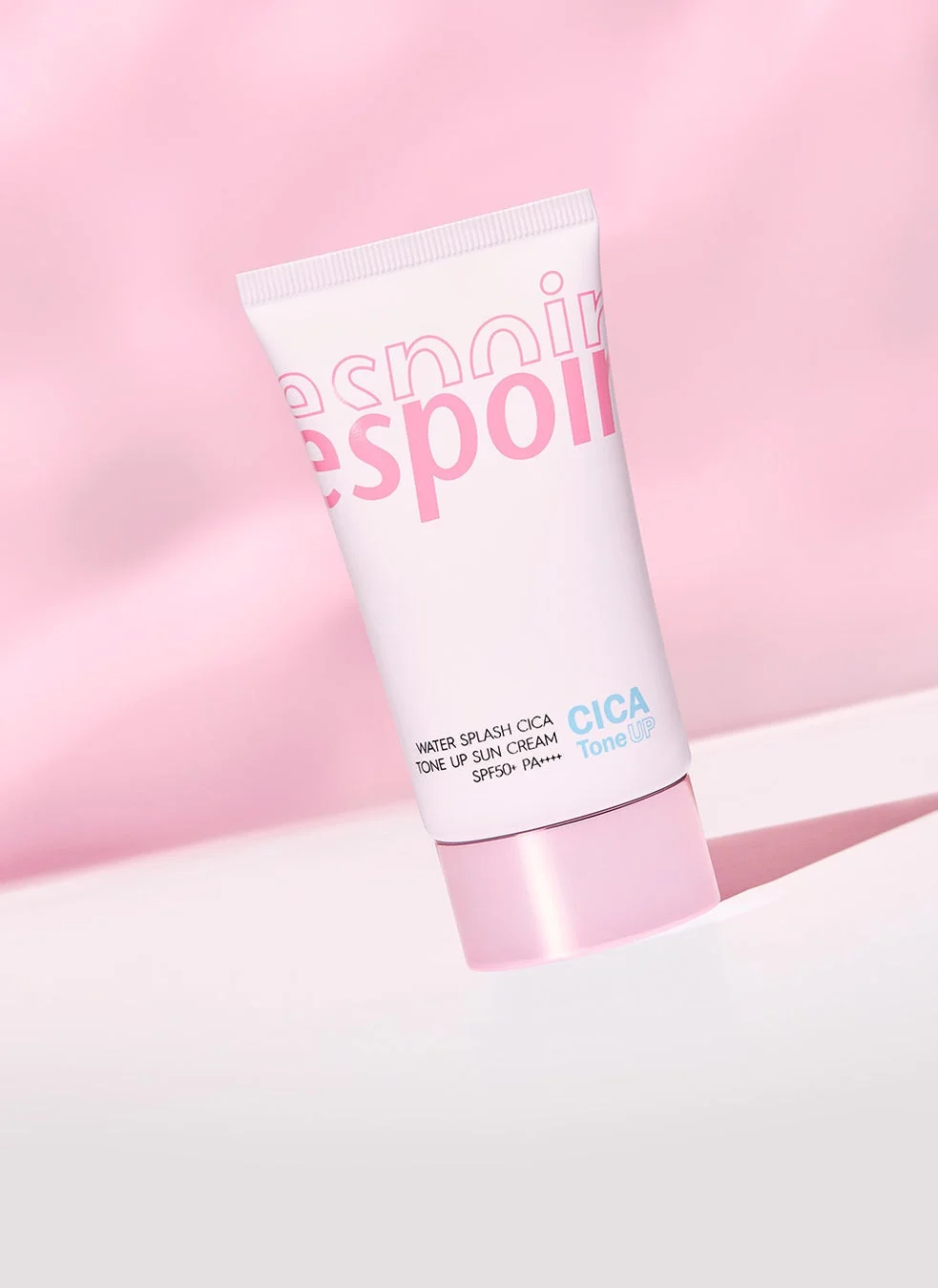 ピンクの背景に置かれた、白とピンクのチューブ型の日焼け止めクリーム「espoir WATER SPLASH CICA TONE UP SUN CREAM SPF50+ PA++++」の画像です。