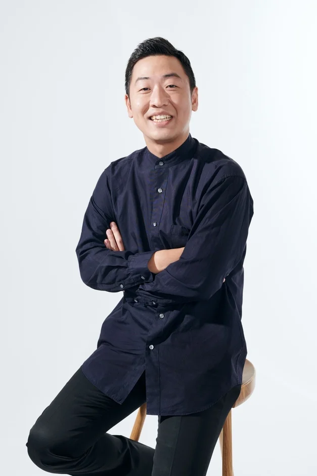 笑顔で腕組みをする指揮者 横山奏氏