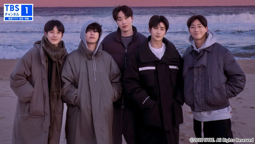 冬の海辺で厚手のコートを着た5人の男性