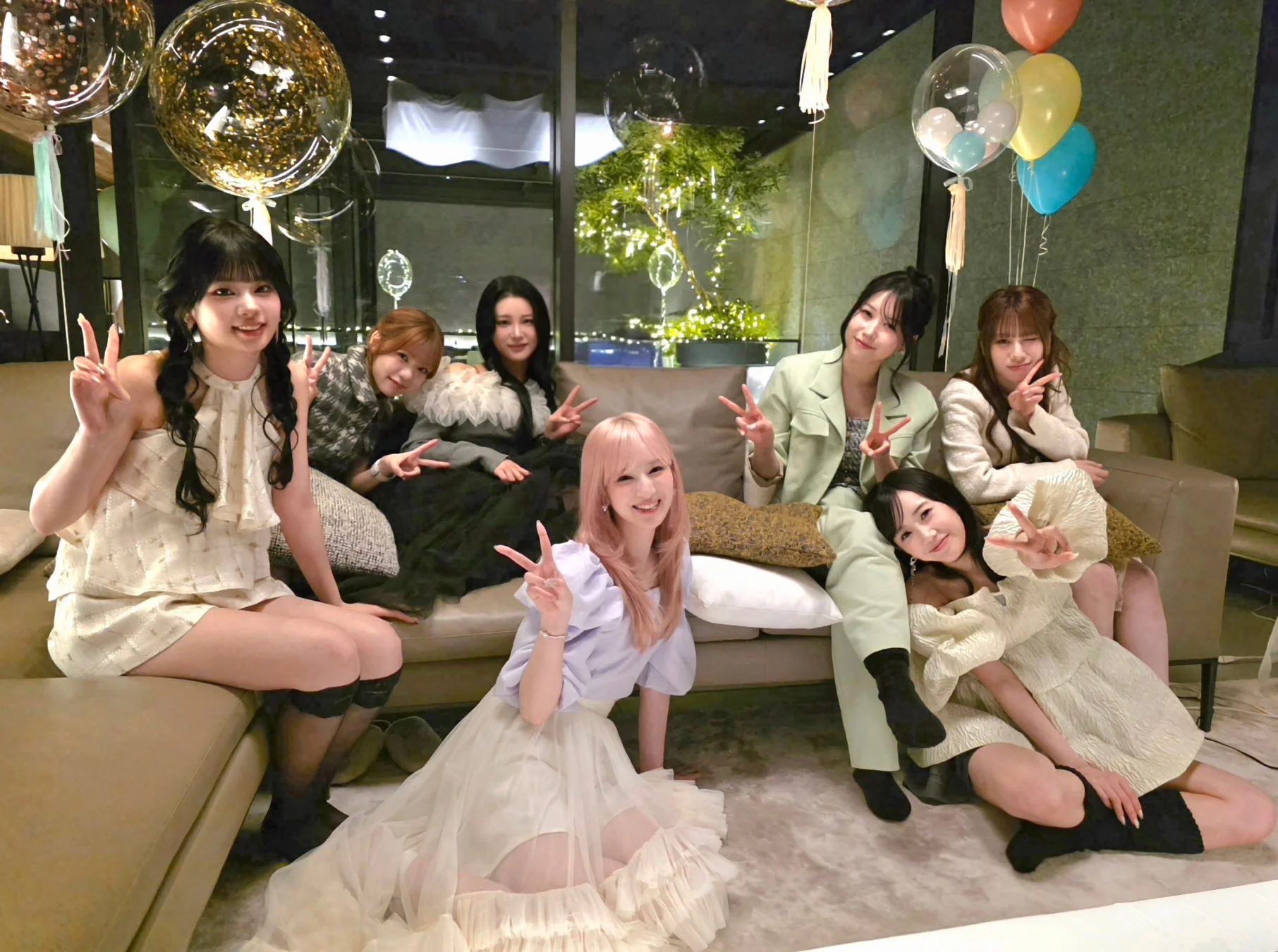 室内で8人の女性たちが集まり、笑顔でピースサインをしながら記念撮影をしている様子です。風船で飾られた空間で、パーティーのような楽しい雰囲気が伝わってきます。