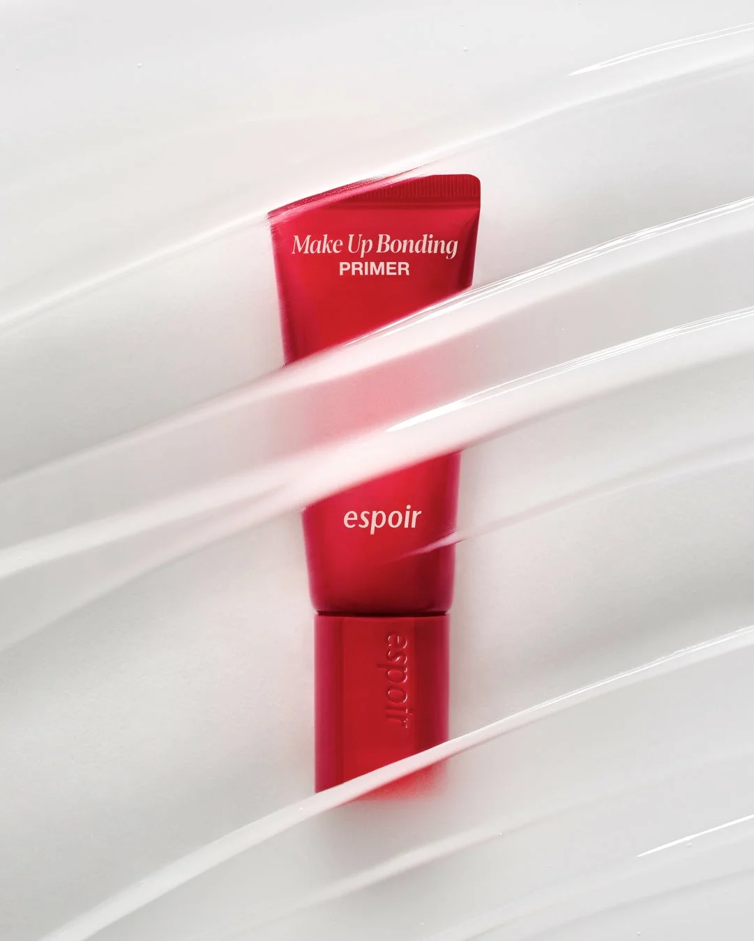 赤いチューブ状のespoirの「Make Up Bonding PRIMER」が、白いクリームのようなテクスチャーの上に置かれている商品写真です。