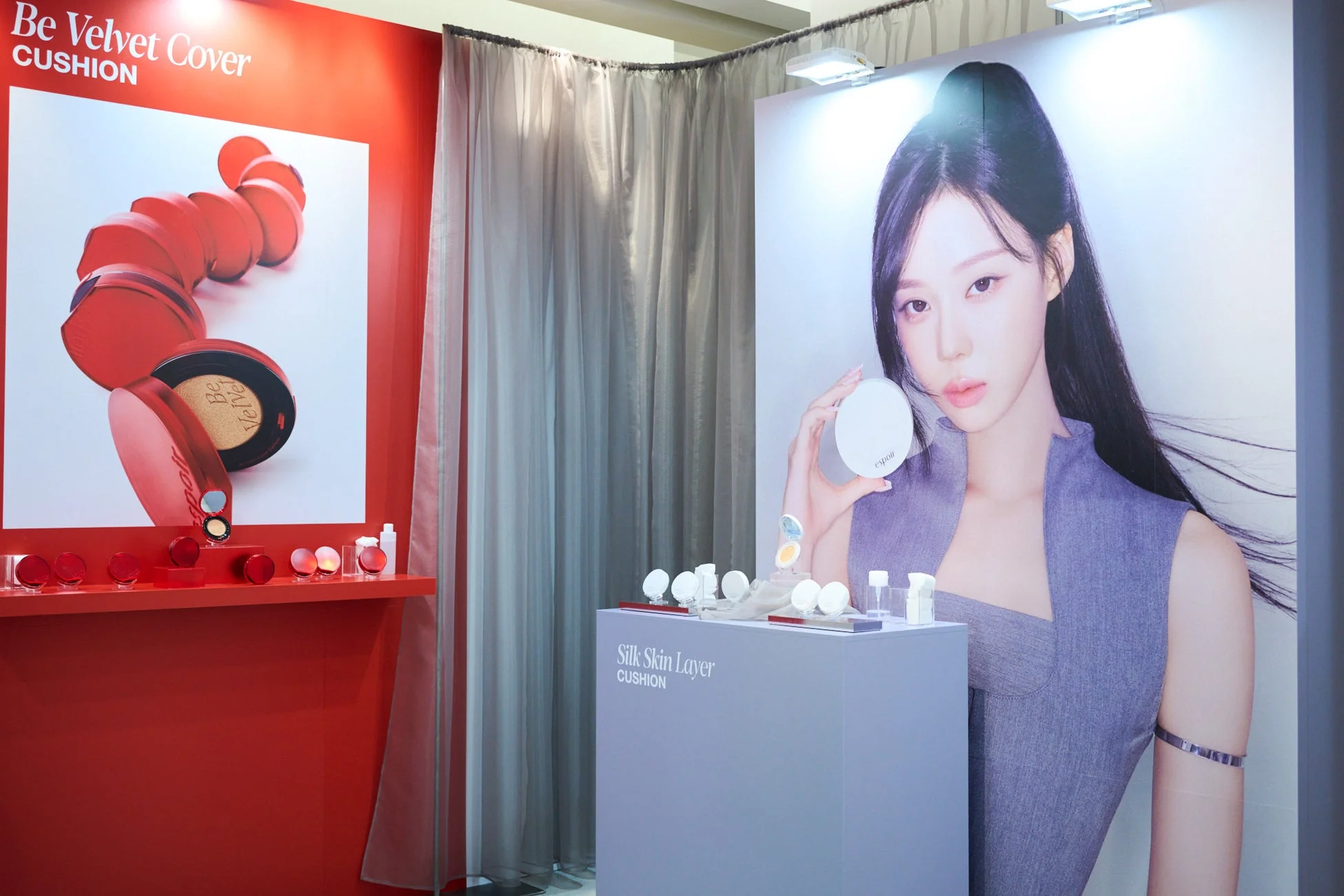 espoirの化粧品プロモーション展示の様子。赤い壁には「Be Velvet Cover CUSHION」が、モデルのポスターがある台には「Silk Skin Layer CUSHION」が展示されており、クッションファンデーションが強調されている。