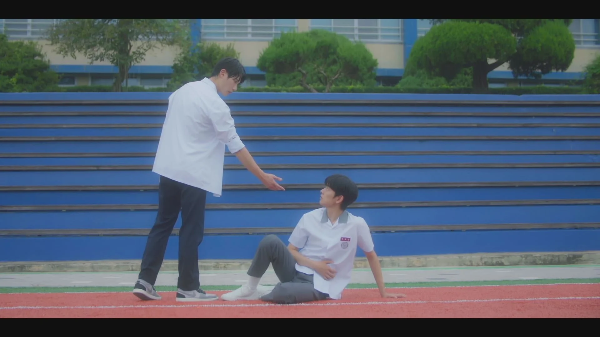 陸上競技場で手を差し伸べる学生