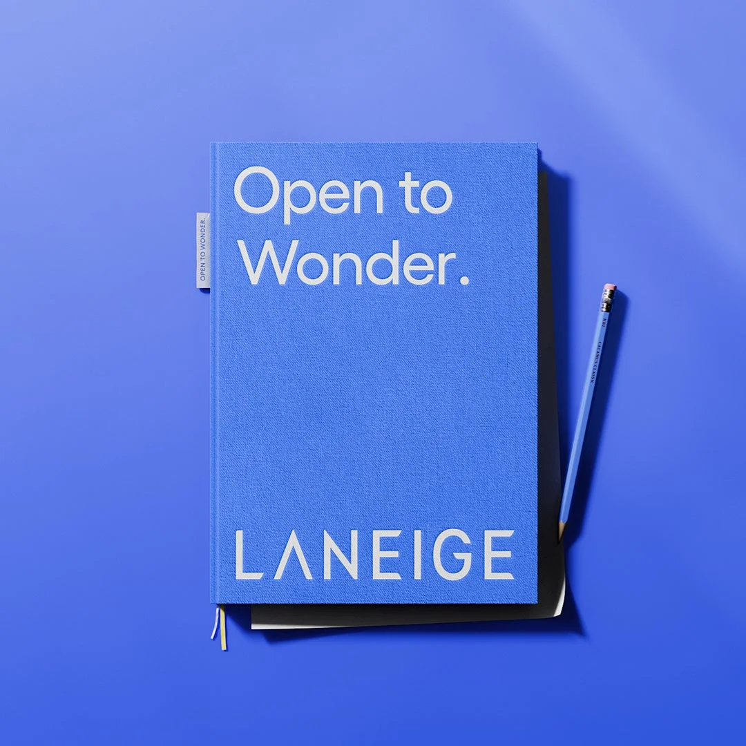 鮮やかな青いノートに「Open to Wonder.」と「LANEIGE」の文字が書かれている