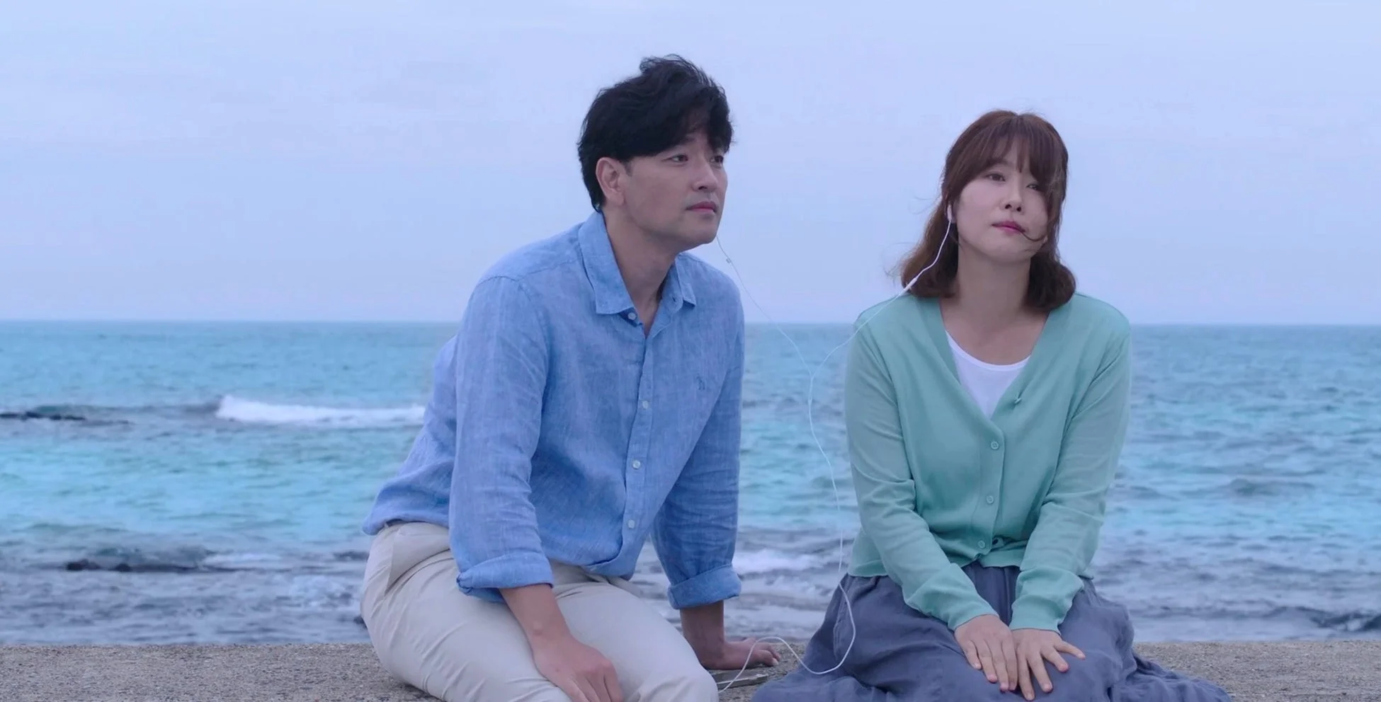 カップルがイヤホンを分け合う