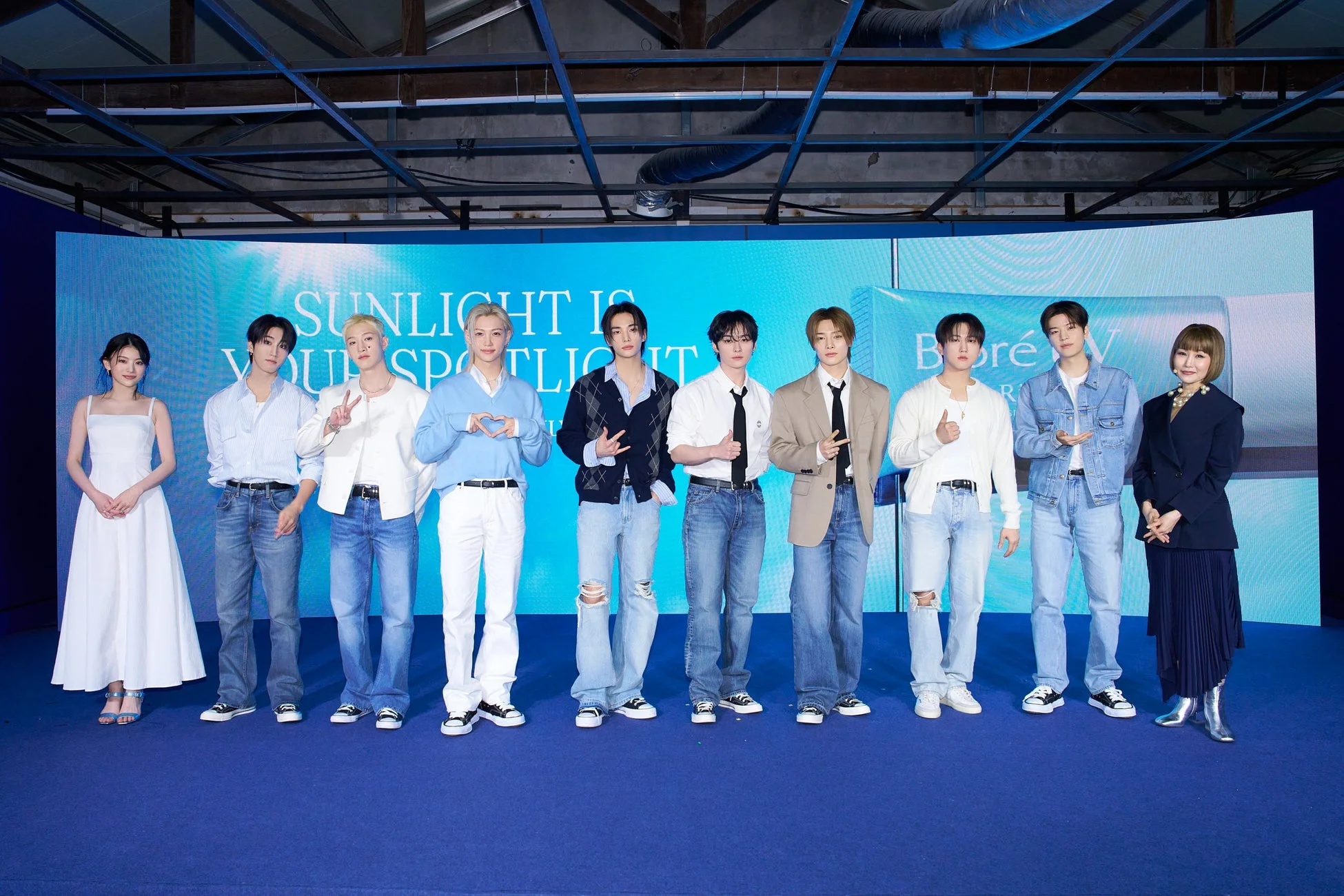 青いステージに立つ10人の男女グループ(男性8名、女性2名)の集合写真です。背景のスクリーンには「SUNLIGHT IS YOUR SPOTLIGHT」という文字と「Boré」というブランドロゴが見えます。プロモーションイベントか記者会見の様子で、皆カメラ目線でポーズを取っています。