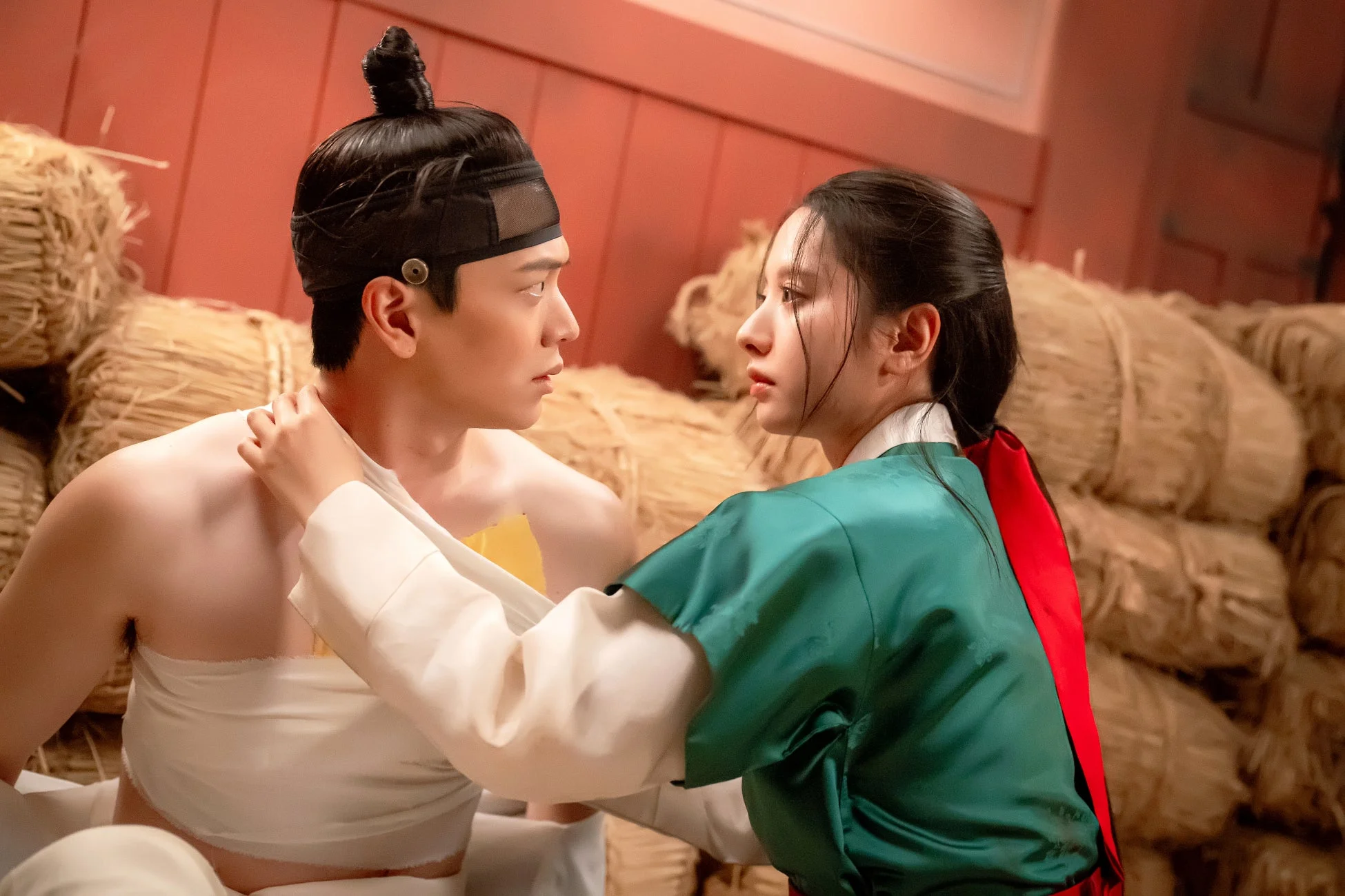 藁が積まれた場所で互いを見つめ合う男女