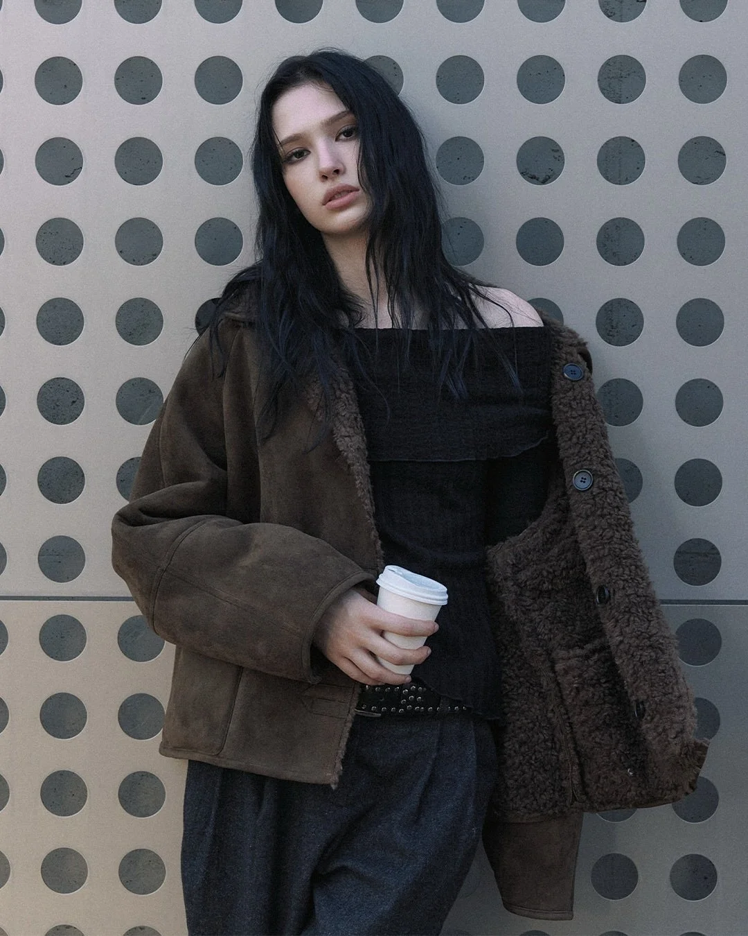 ムートンジャケットとコーヒーカップを持つ女性