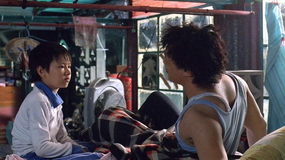 質素な室内で少年と大人が座る